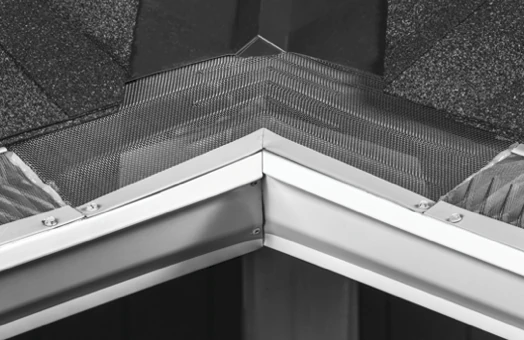 Leaf Deflector High-Flow Inside Miter installed at a white gutter corner beneath a shingle roof valley